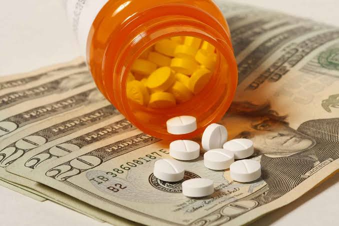 Prescription medication alongside cash, representing the true cost of pharmacy benefits.